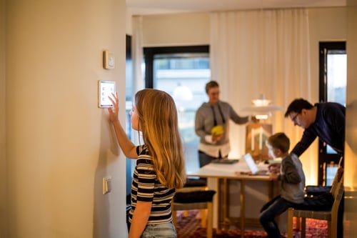 Girl interacting with smart device on wall near family