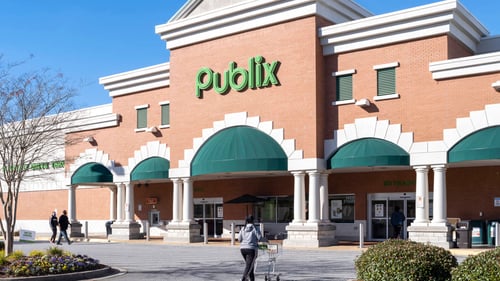 Person with shopping cart walking into Publix with rounded green awnings