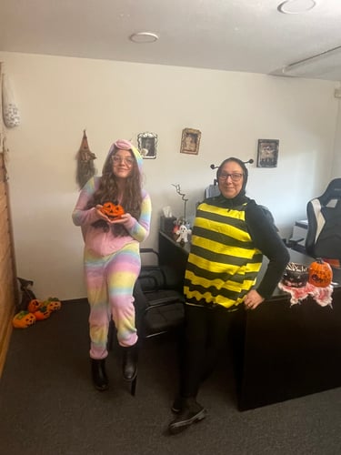Two women dressed up in Halloween costumes are in an office.