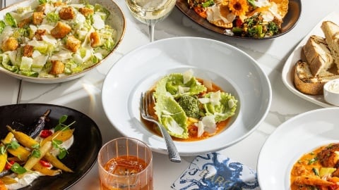 Salad and appetizers with drinks on restaurant table.