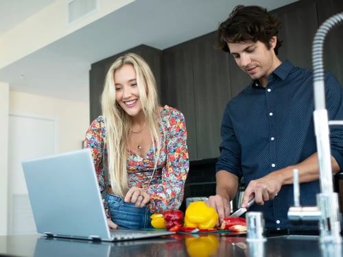 Couple cooking in the kitchen using the internet to watch a cooking show