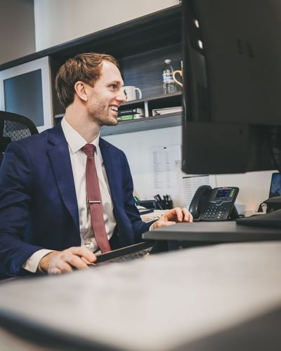 Attorney at his desktop smiling, while scrolling on desktop