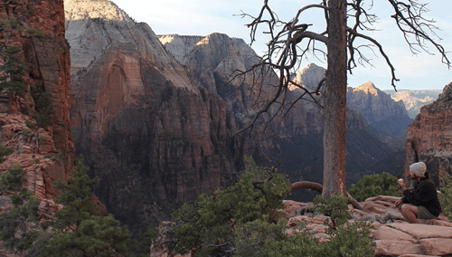 A person sitting on a mountain cliff.