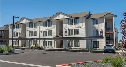 A large white building with a red stripe on the side at Cascade Place Apartment Homes, Molalla