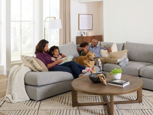 A family sits on the couch with their dog.