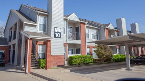 Two story apartment building next to covered car ports