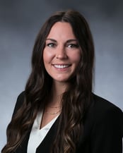 Madeline smiling in front of a gray background.