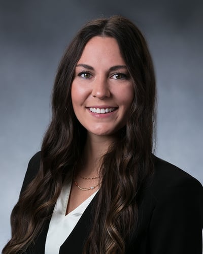 Madeline smiling in front of a gray background.