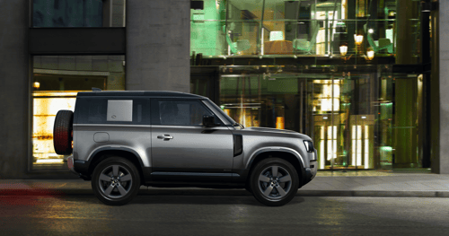Pangea Green Defender 110 parked beside a reflective water surface in a misty rainforest