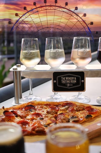Wine flight, pizza, and beer flight with The Wheel sunset view at The Winery and Tasting Room by Brewlando at ICON Park Orlando