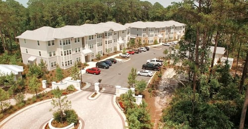 Aerial view of The Sanctuary at 331 apartment community in Santa Rosa Beach showing building exteriors, parking, and surrounding forest.