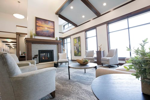 A concierge greets new residents and visitors to the Gathering Place in the main building. Residents here participate in programming, dining and group activities. The front room features a warm fireplace and comfortable furniture with multiple seating options.
