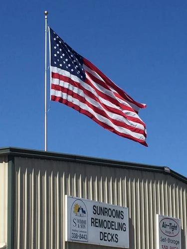 American flag flying over Swimme & Son building contractors in North Carolina, with signage for sunrooms, remodeling, and deck services.