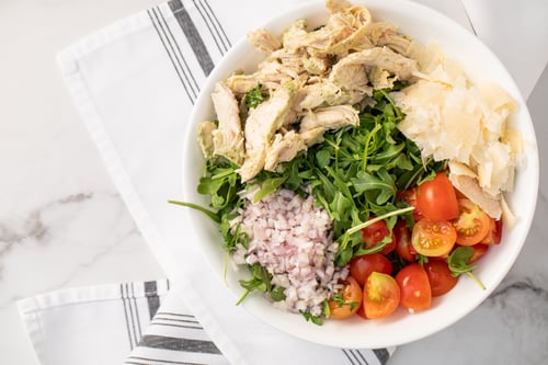 Overhead picture of an Arugula Salad sitting on a linen
