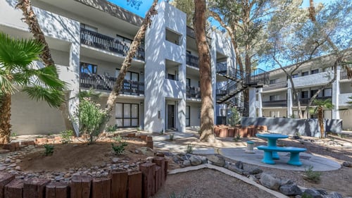 a courtyard with a blue bench and a building with trees at Evoq Apartment Homes, Las Vegas Nevada