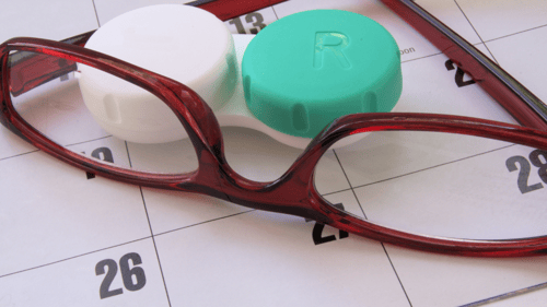 glasses and contact lenses laying on a desk calendar