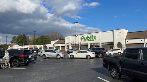 Woman walking through full parking lot of Publix