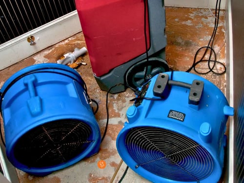 Water damage restoration equipment with air movers and dehumidifier drying wet floor in NW Cobb home