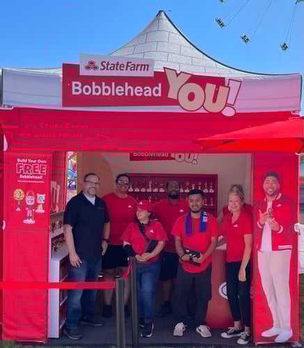 Team members and agent standing under a red tent.