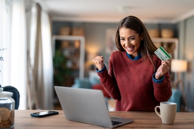 Happy woman shopping online with credit card and laptop at home