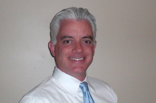 Agent Sean McCarthy standing and smiling wearing white button up shirt with light blue tie