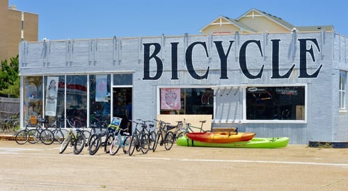 Front entrance of Outer Banks Bicycle Shop in Kill Devil Hills, NC with bicycles and kayaks outside