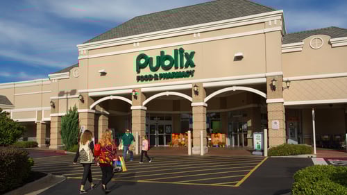 Two people walking towards and two people walking away from entrance of Publix at Vineyards at Chateau Elan