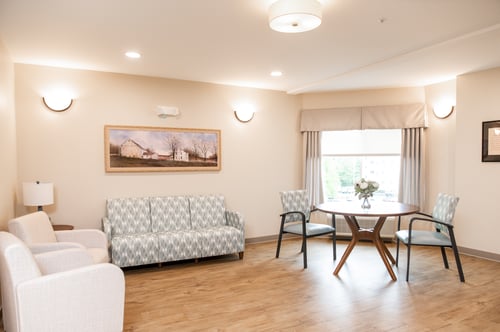 Summer Hill of Wayne beautiful lounge area for residents, including brand new furniture, paintings on the walls, and a large window