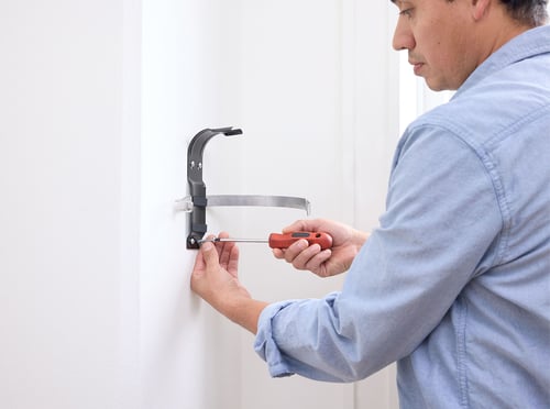 A man installs a fire extinguisher bracket on the wall.