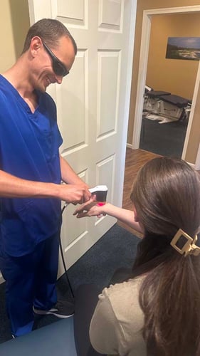 Dr. Gage Kirstein performing laser therapy on a patient's hand