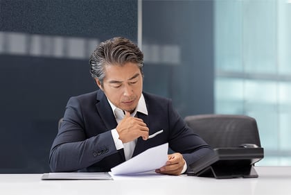 Businessman reading documents sitting at his desk