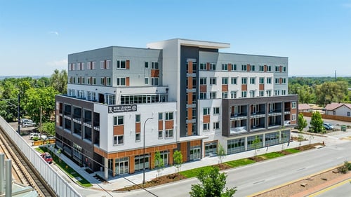 A modern multi-story building with a mix of grey and brown exterior walls at Wadsworth Station in Lakewood, CO, 80214