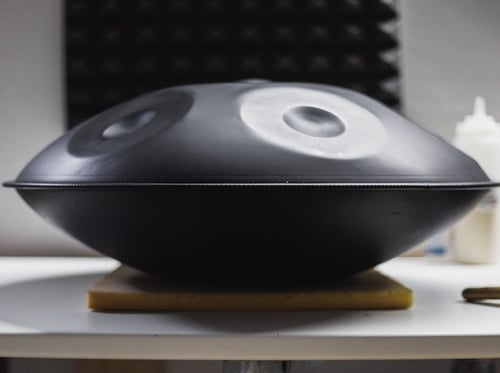 Eine Black Magic Handpan aus nitriertem Stahl steht auf einem Tisch. Diese Handpan kaufen und ausprobieren im Handpan Showroom Hamburg