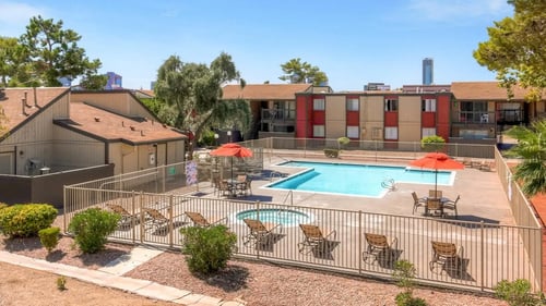 A pool surrounded by a fence and chairs at Namaste Apartments, Las Vegas, NV, 89102