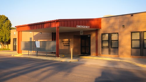 Emergency room entrance with a red awning on a brown brick building with white letters that says "emergency".