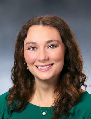 Christine Dumm, PA-C smiling in front of a gray backdrop with a dark green blouse.