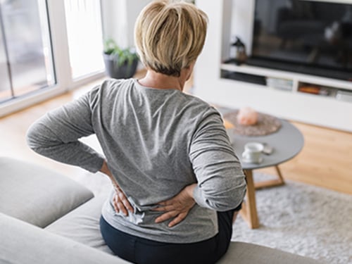 woman in living room experiencing back pain