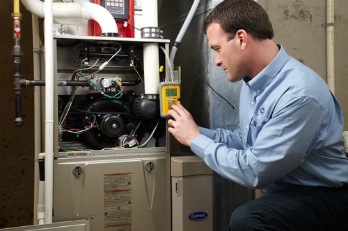A Carrier dealer performs annual HVAC maintenance on a furnace