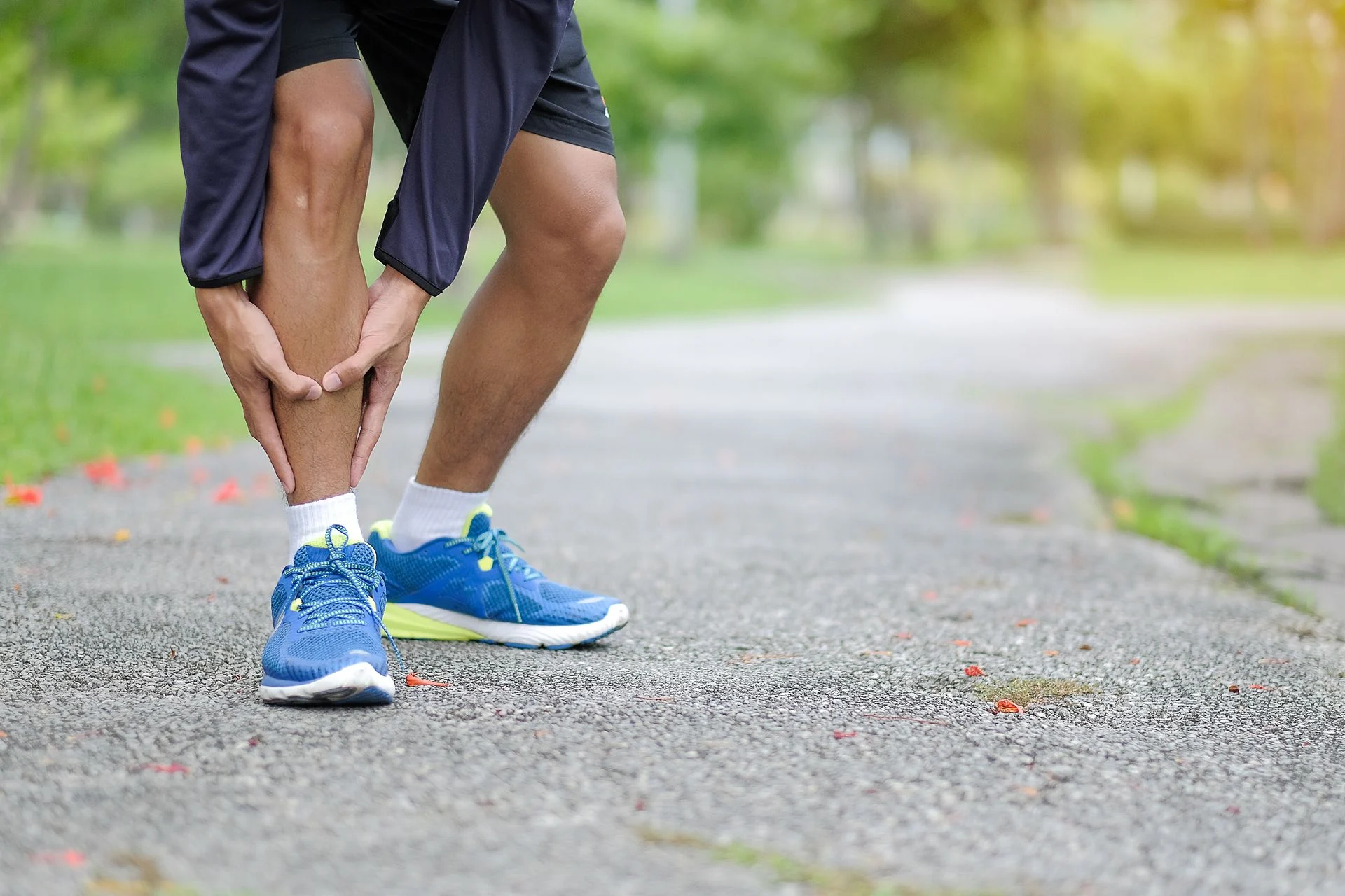 Person on running trail holding their calf in pain