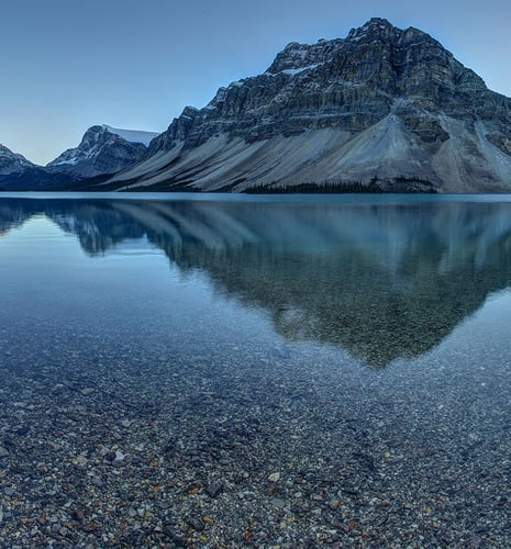 A calm lake with mountains in the background.
