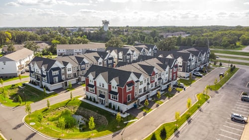 an aerial view of a townhome community with cars parked in front of it at Field and Grove Townhomes, in Champlin, MN