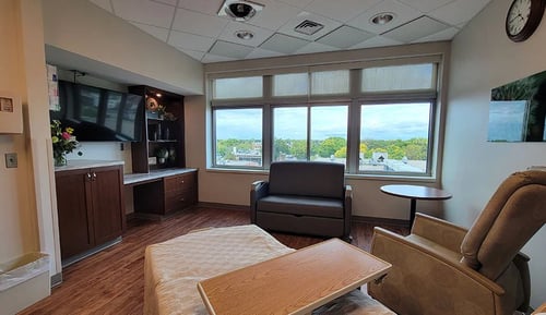 A view of the private suite for families with additional needs featuring a bed, recliner and TV.