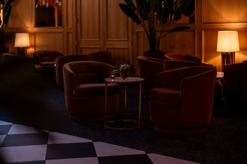 Velvet swivel armchairs glowing softly in warm candlelight.