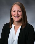 Ally Judnick smiling in front of a gray background.