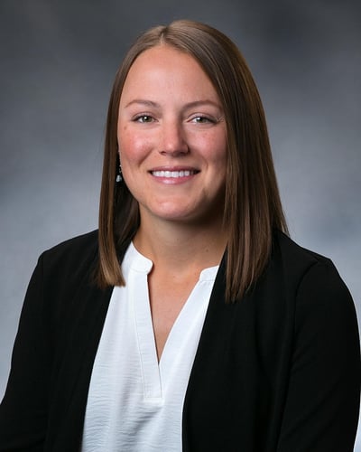 Ally Judnick smiling in front of a gray background.