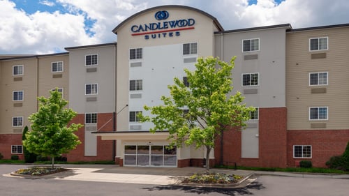Hotel exterior with brick facade, covered entrance, and parking.
