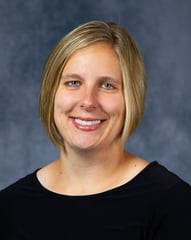 Jessica smiling in front of a gray background.