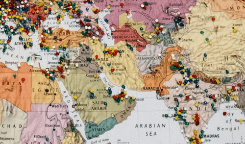 A world map section highlights the Middle East and surrounding regions, covered with multicolored pushpins marking various locations, suggesting diverse and rich travel activities.