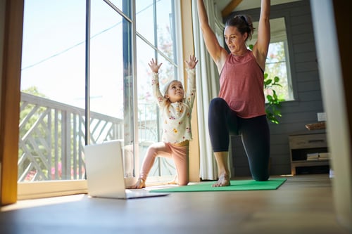 Mom and daughter doing yoga watching laptop