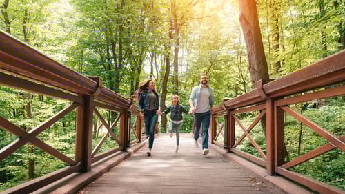 Couple running across a bridge in the woods